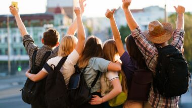 Student travelers with backpacks rising hands, joy and positivity