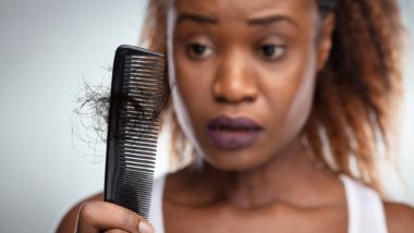 Woman looking at hair loss in comb regarding Deva Concepts class action lawsuit accusing the companies DevaCurl products of causing hair loss and damage