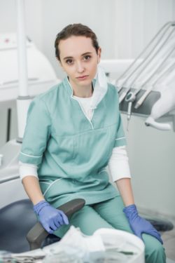 Female dentist sitting in dental office regarding the class action lawsuit filed against a insurance company for denying business loss claims amid COVID-19