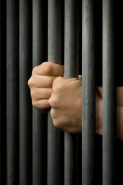 Hands grasping prison bars regarding the Mission Institution class action lawsuit filed over CSC's COVID-19 response