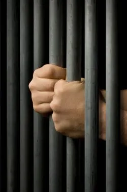 Hands grasping prison bars regarding the Mission Institution class action lawsuit filed over CSC's COVID-19 response