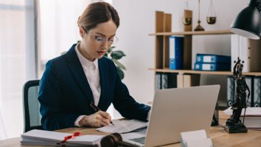 lawyer working at her desk regarding information on who covers the cost of a class action lawyer