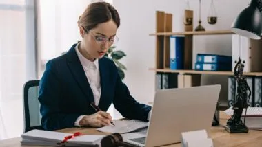 lawyer working at her desk regarding information on who covers the cost of a class action lawyer