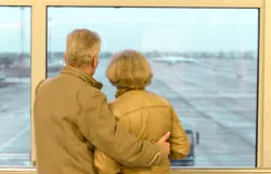 Older couple looking out the airport window regarding the class action filed against Air Canada over flight passes and retirement benefits