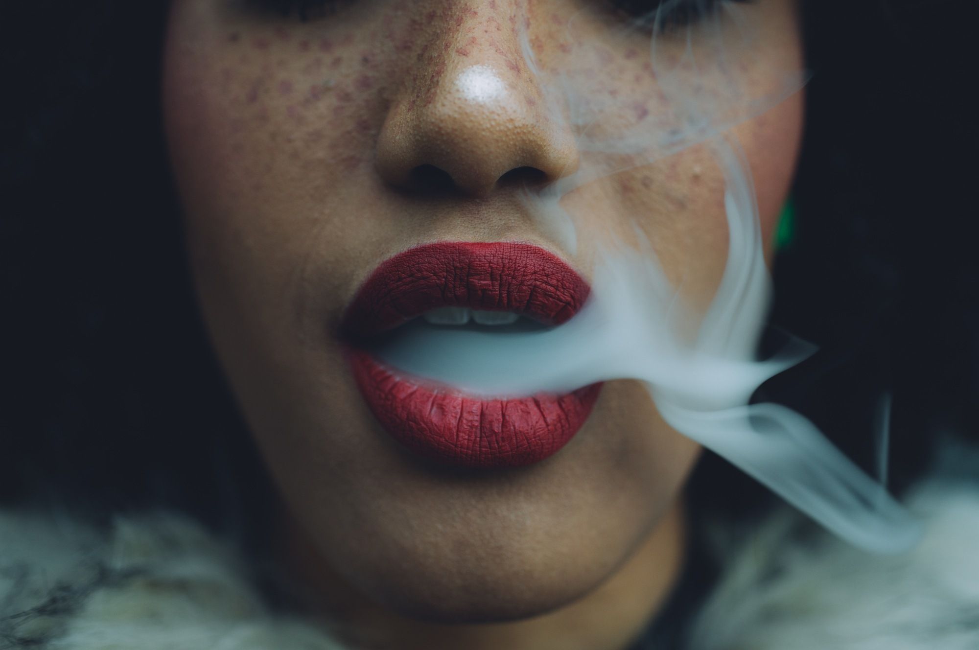 woman blowing smoke out her mouth regarding the Juul e-cigarette class action lawsuit claiming the company used deceptive marketing tactics