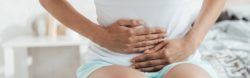 Woman in pain holding her abdominal area regarding the AMS transvaginal mesh settlement