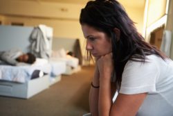 Woman sitting with a woman sleeping in the background regarding the homeless shelter lawsuit filed against the city of Toronto over its COVID-19 response 