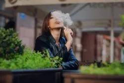 Woman vaping regarding the Juul e-cigarette class action lawsuit filed against the company over its marketing to teenagers