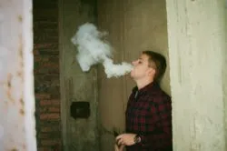Boy vaping in alley regarding whether JUUL pods are bad for you