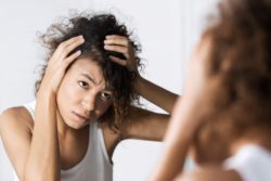 Concerned woman looking at her scalp regarding the Deva Concepts class action lawsuit filed