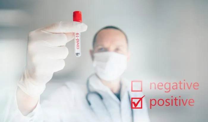 Doctor holding a positive COVID-19 labeled test tube regarding the false COVID-19 positive test results class action lawsuit to be filed against Lab