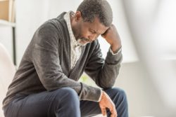 Man looking down upset regarding the nursing homes failed COVID-19 response class action lawsuit expanding to include Sienna Senior Living Inc.