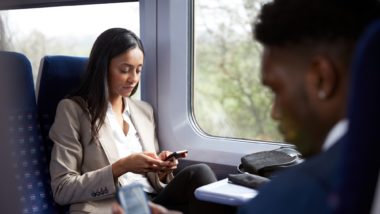 Woman and man looking at their phones on the train regarding information on text spam and how to prevent it