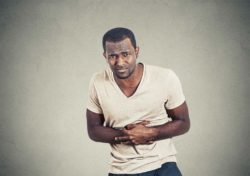 Man clutching his stomach chest area regarding the Zantac class action lawsuit regarding the drug's cancer risk