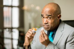 Man holding pill looking worried about takig it regarding the city of Grand Prairie considering to join a opioid class action lawsuit 