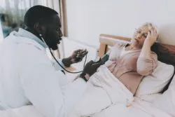 Nurse taking care of elderly woman regarding the Revera class action lawsuit over the nursing home's response to COVID-19