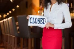 Server holding closed sign regarding the Toronto restaurant filing a lawsuit against its insurance company over denied COVID-19 losses claims 