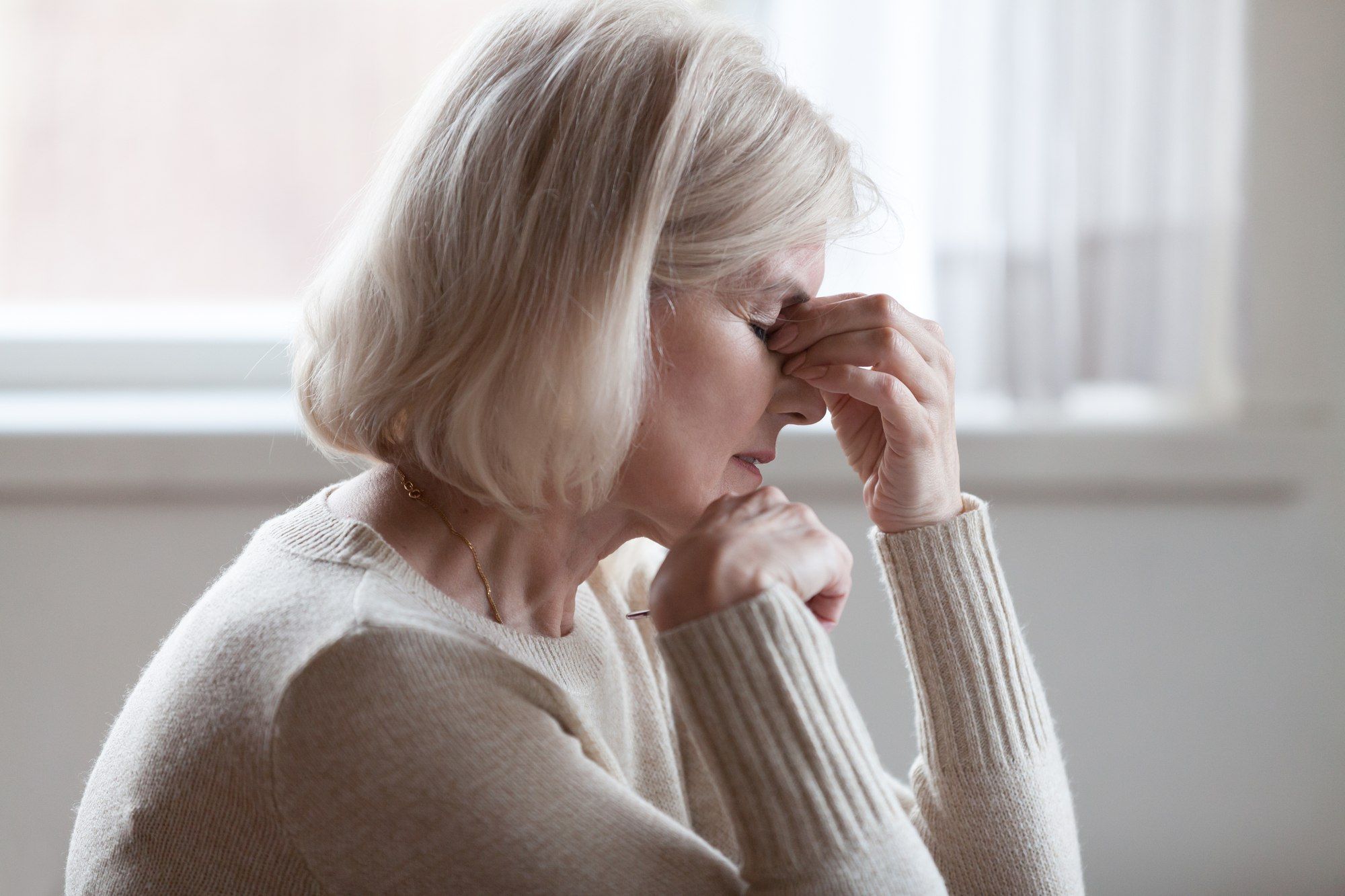 Woman touching her face in pain regarding the Elmiron class action lawsuit alleging the drug causes vision loss