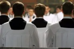 blurry view of young clerics in mass regarding the members of the Clerics of St. Viator being arrested for sexual abuse allegations