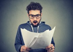 Man looking upset at papers regarding the gym service fees class action lawsuit filed 