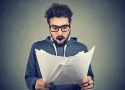 Man looking upset at papers regarding the gym service fees class action lawsuit filed