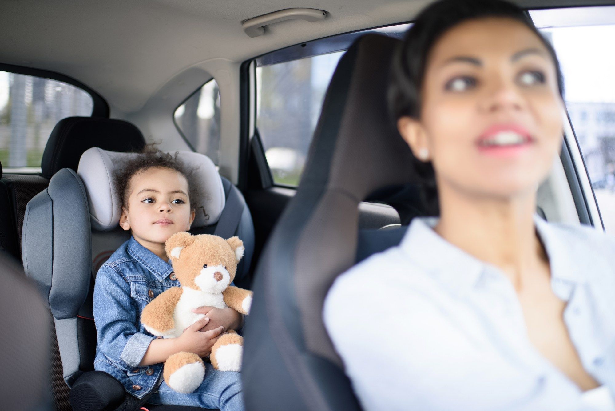 Woman looking back at baby in car seat regarding the Big Kid Booster seat class action lawsuit filed 