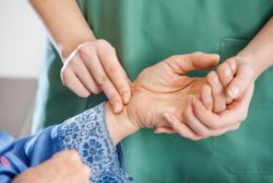 nurse checking person's pulse regarding the Orchard Villa class action lawsuit filed Amid COVID-19 deaths