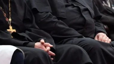 people sitting in catholic mass in black robes regarding the five members of the Clerics of St. Viator being arrested for sexual abuse allegations