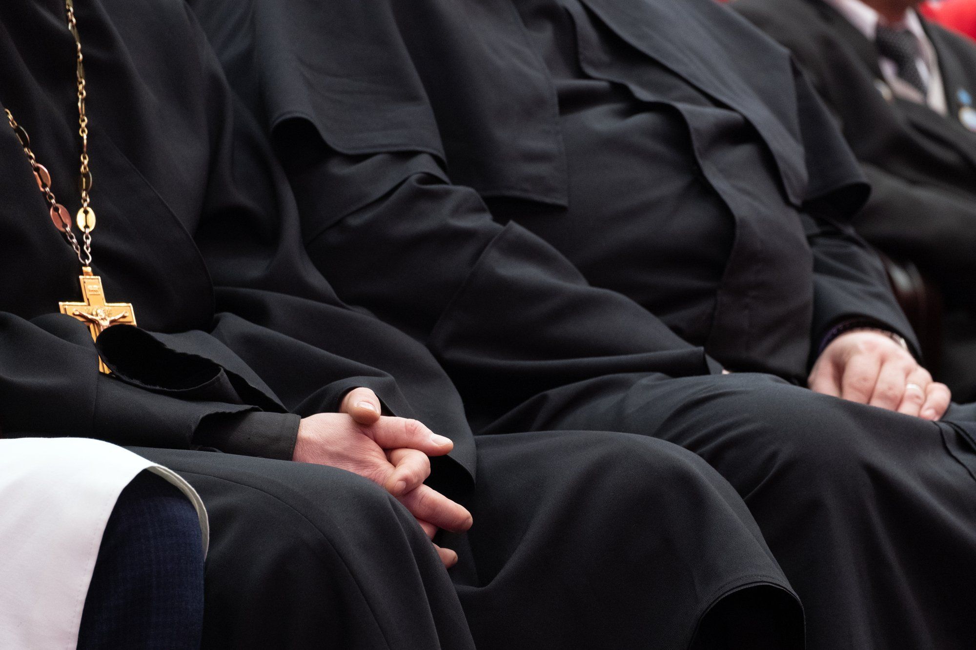 people sitting in catholic mass in black robes regarding the five members of the Clerics of St. Viator being arrested for sexual abuse allegations 