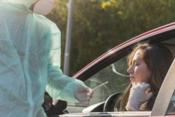 Person in protective suit getting a sample from driver regarding the COVID-19 lawsuit filed against Quebec over it's pandemic measures 