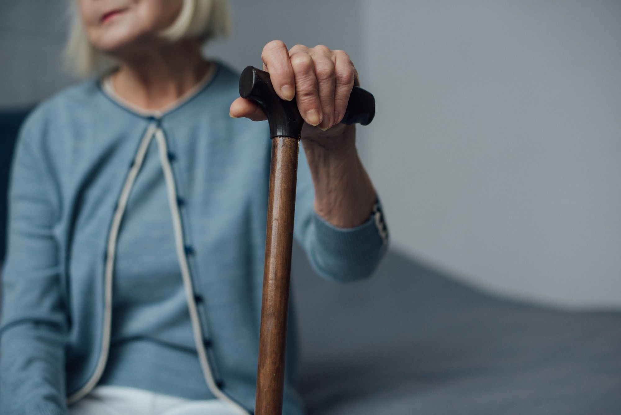 Senior woman sitting holding cane regarding the Northwood long-term care COVID-19 class action lawsuit 