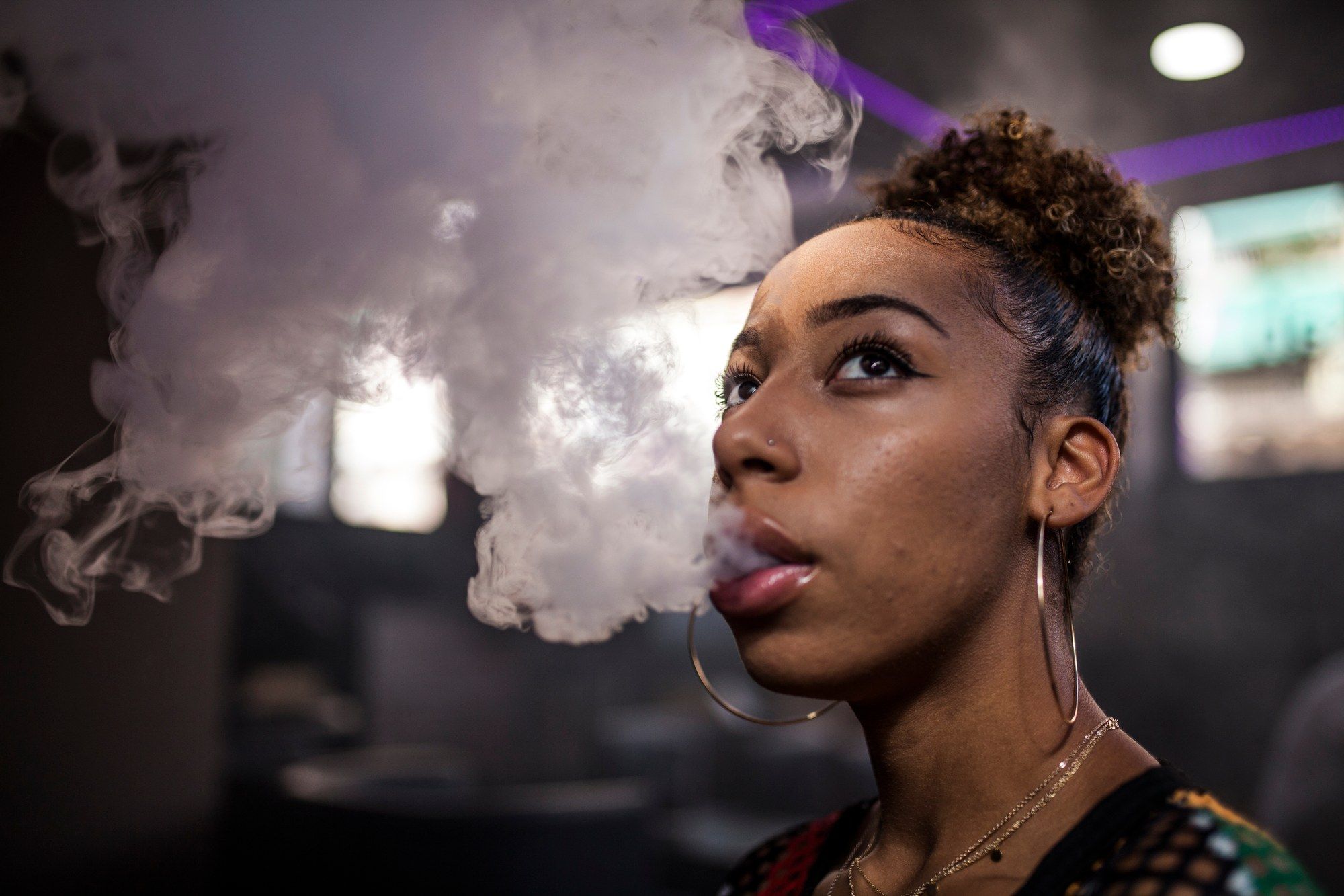 Woman vaping blowing smoke regarding the JUUL health risks class action lawsuit filed
