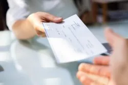 Hands exchanging paychecks regarding the Phoenix pay system settlement reached