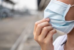 inmate holding blue mask to face