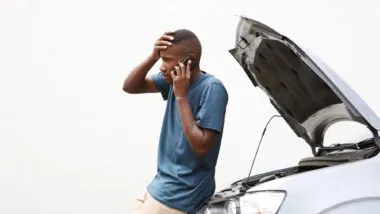 Man standing next to a stalled car regarding the Denso fuel pump defect