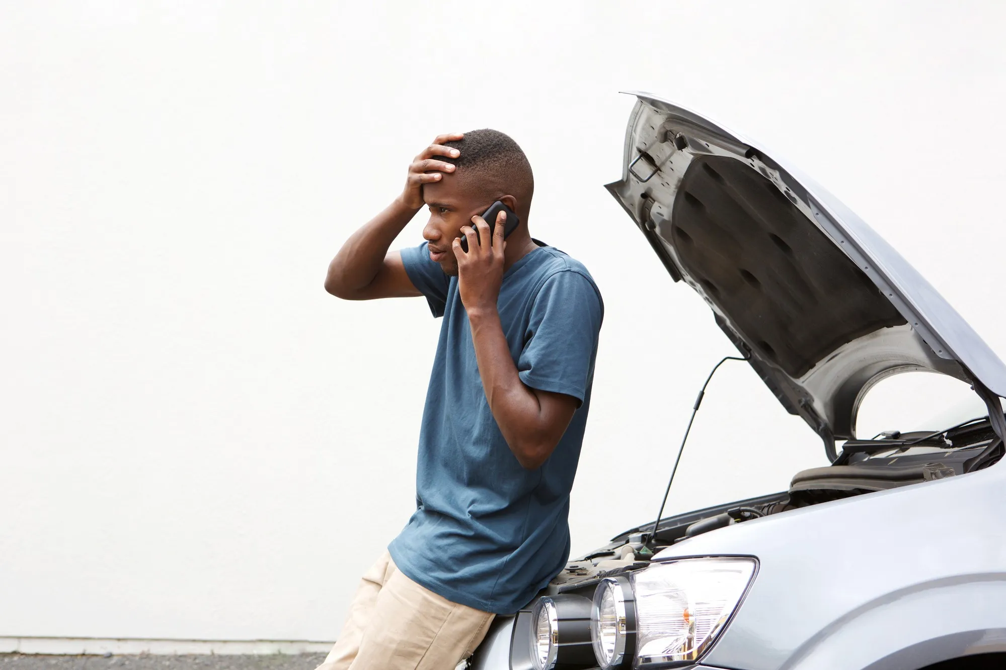 Man standing next to a stalled car regarding the Denso fuel pump defect 