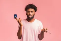 man shocked holding a card regarding the prepaid visa card class action lawsuit settlement reached 