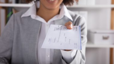 Woman handing over check regarding the Phoenix pay system settlement reached