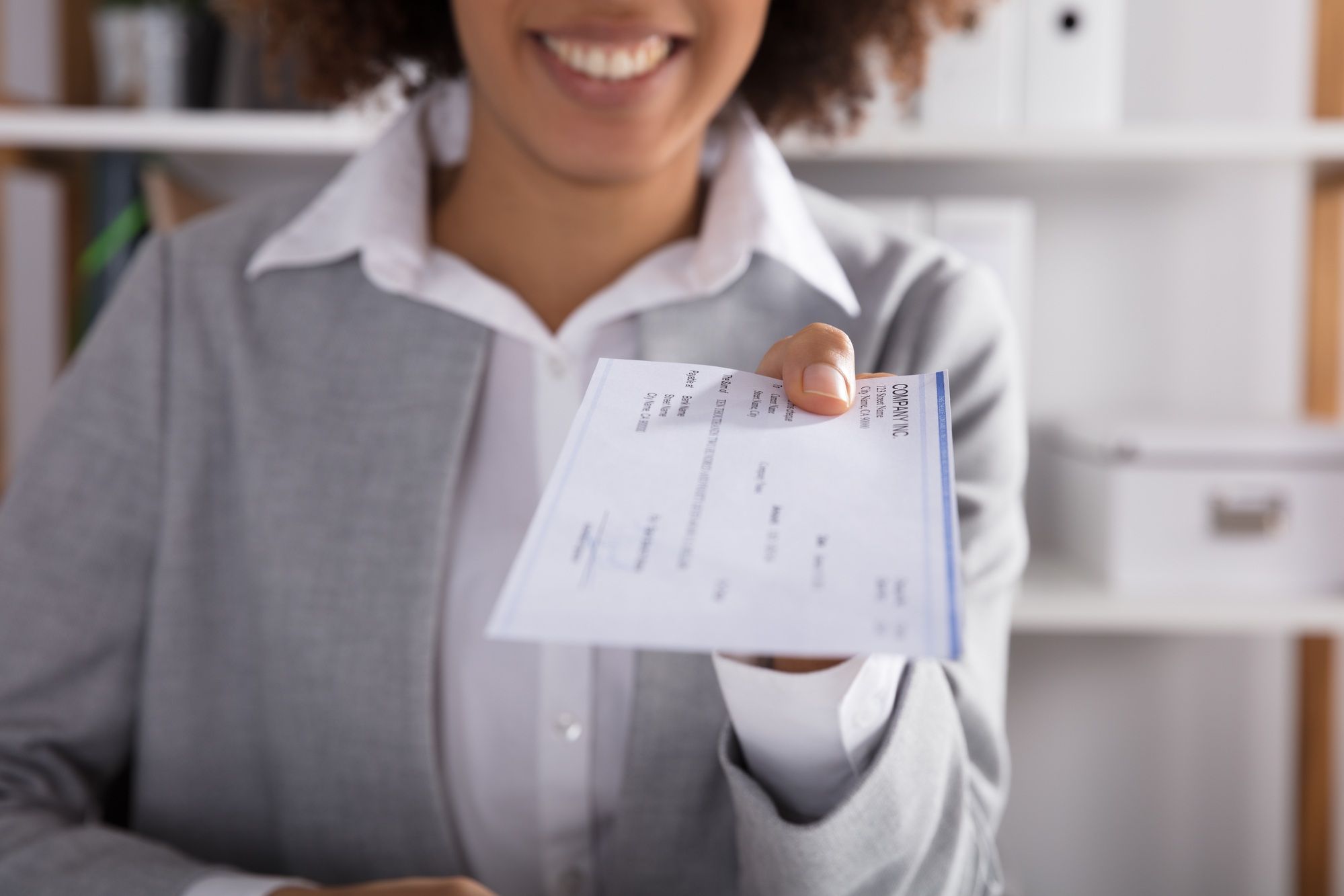 Woman handing over check regarding the Phoenix pay system settlement reached