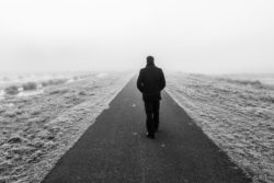 black and white photo of roma refugee walking alone as settlement is reached