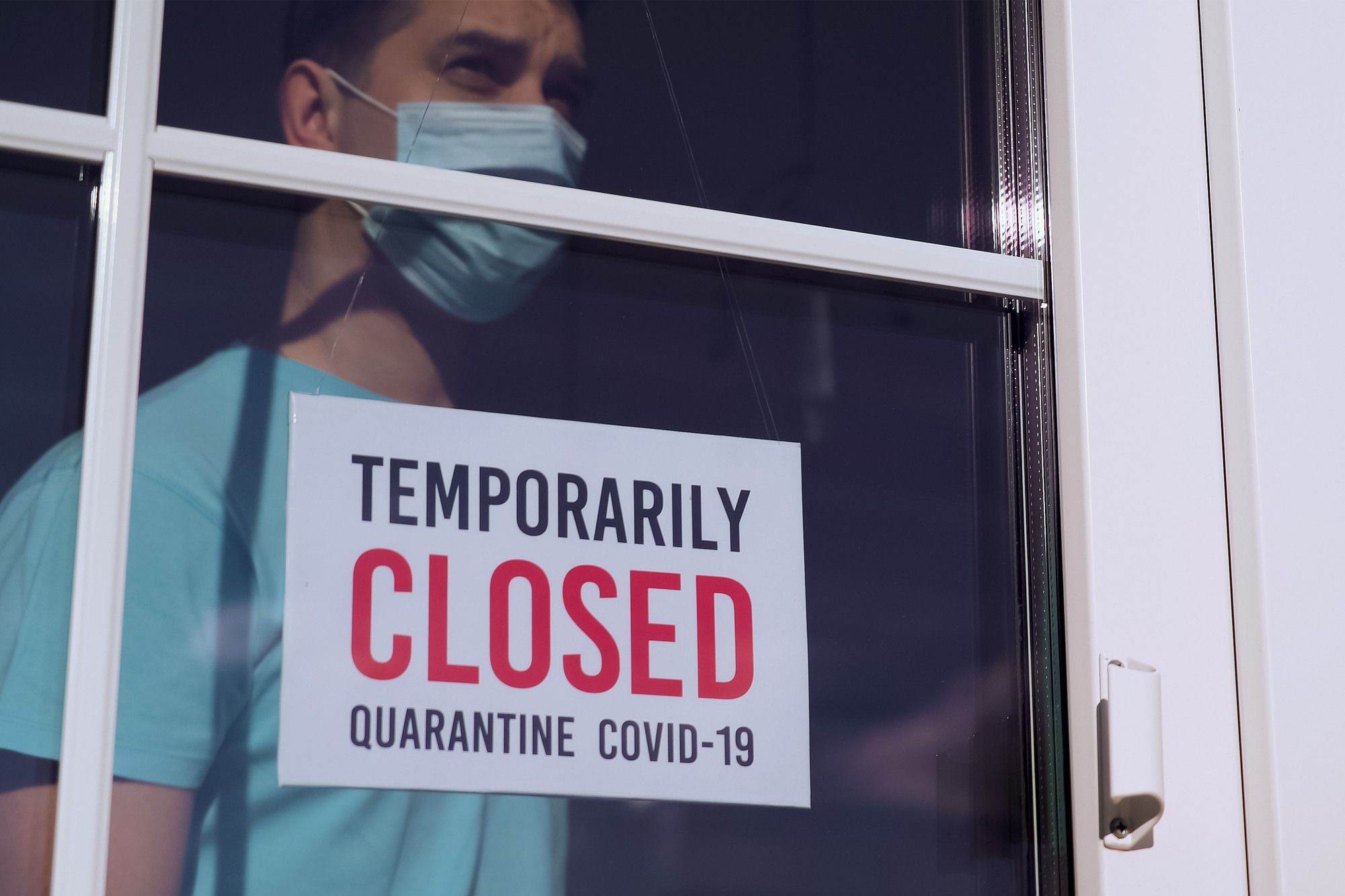 Man standing behind a closed sign regarding information on business interruption insurance 