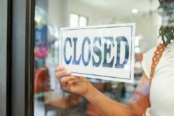 Person putting up closed sign regarding the Great Clips class action lawsuit