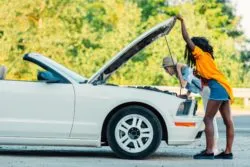two women checking under hood of car for defects