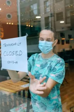Woman hanging closed sign regarding information on business interruption insurance