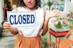 Business owner with closed sign regarding the Economic Mutual Insurance Company class action lawsuit filed