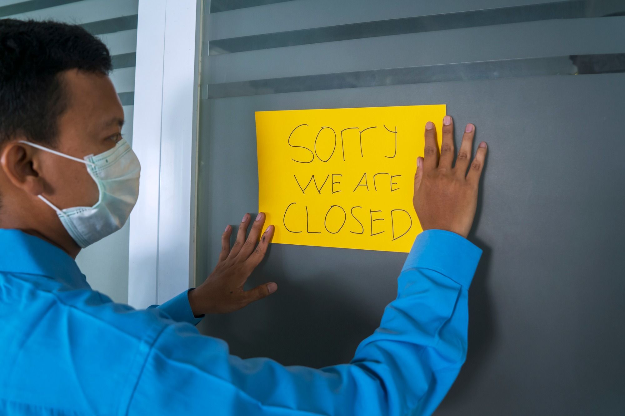 Man putting up closed sign regarding the Coalition for Hardest Hit Businesses