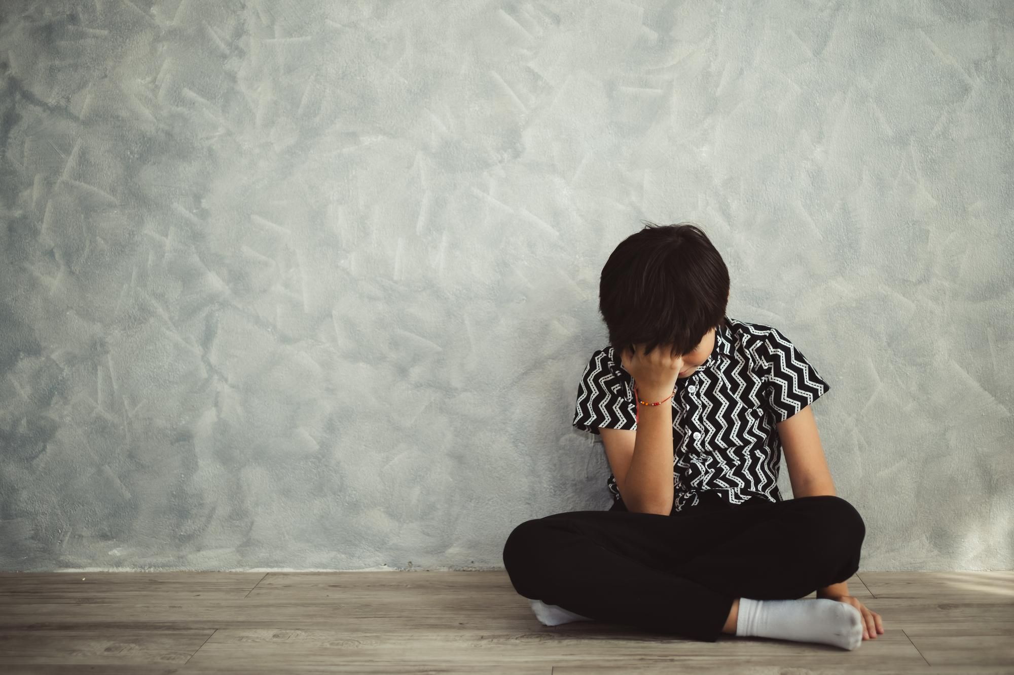 Sad boy sitting down regarding the First Nations Children class action lawsuits