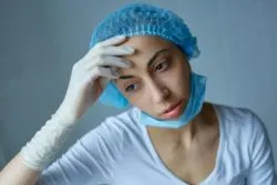 Tired sad nurse regarding the Hospital Ordered to Take Over Ottawa Long-term Care Homes Amid Outbreaks