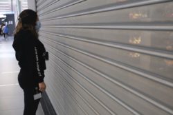 woman in mask in front of closed shop due to cover