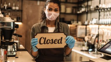 Business owner holding a closed sign amid cOVID regarding information on What Should You Know When Filing a Business Interruption Claim Letter?